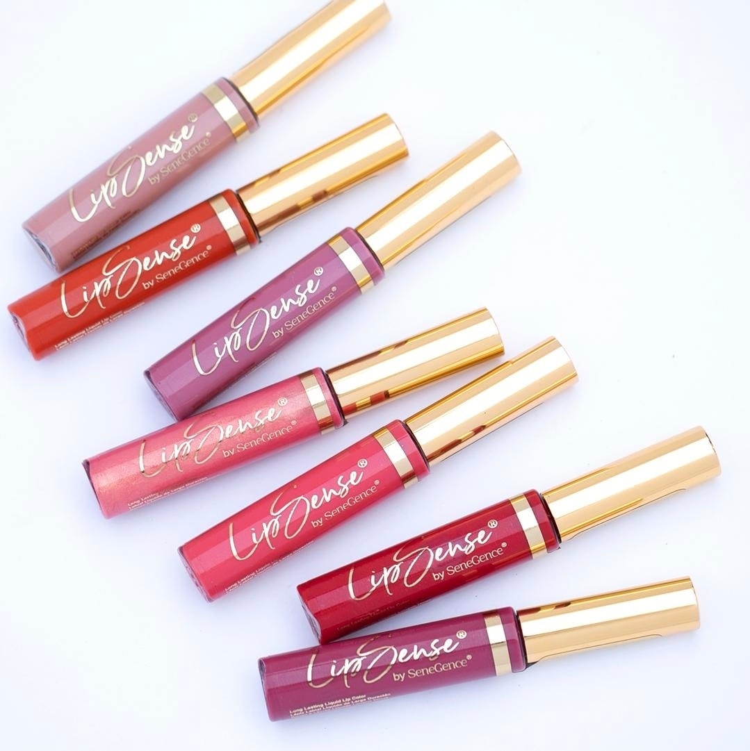 Six LipSense liquid lip colors with gold caps arranged on a white background